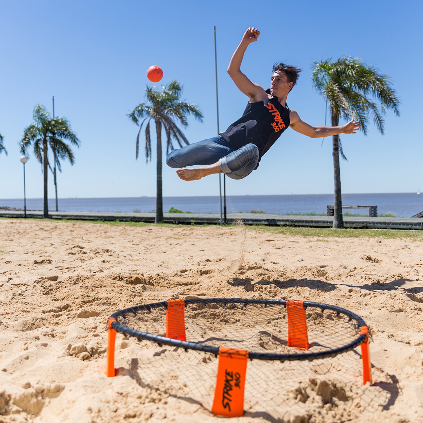 Jugador de Strike 360 saltando junto a la red, en un parque frente al río